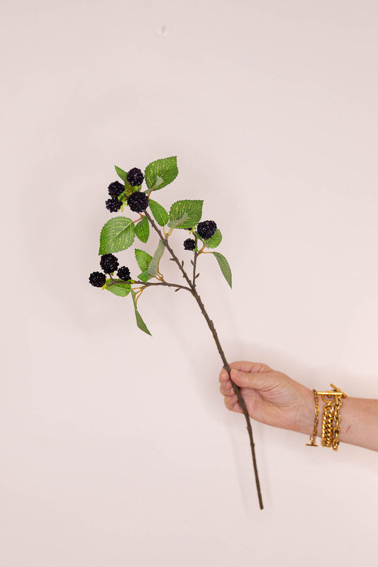 An artificial blackberry branch with green leaves and dark berries.