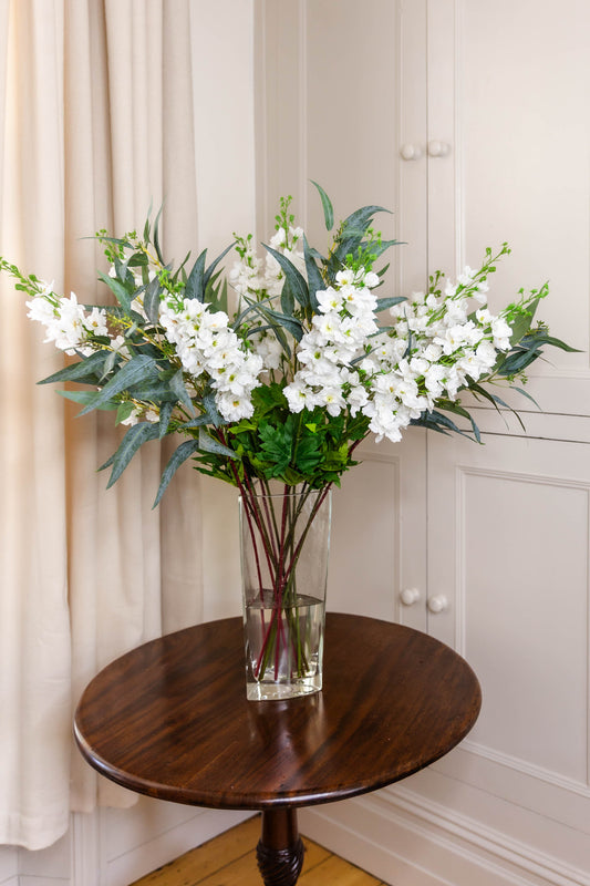 The Morden arrangement features seven faux real-touch ivory Delphinium Larkspur stems and five stems of faux Eucalyptus Nicolii.
