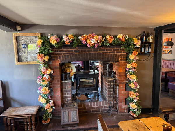 Summer faux floral green ruscus garland installation at The Plough Inn Norwood Green with yellow peonies, pink scabiosas, orange hydrangeas, white chrysanthemums, pink and nude dahlias 