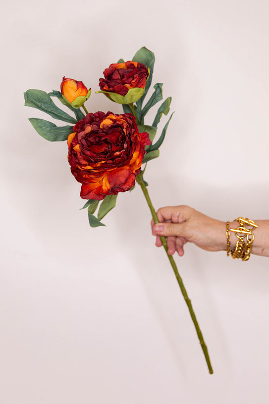 A faux floral long-stemmed dried touch russet Peony with green leaves .