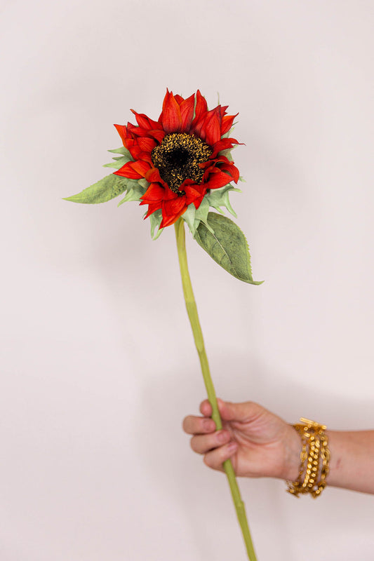 An artificial faux floral single real-touch red sunflower with green leaves and a long stem.